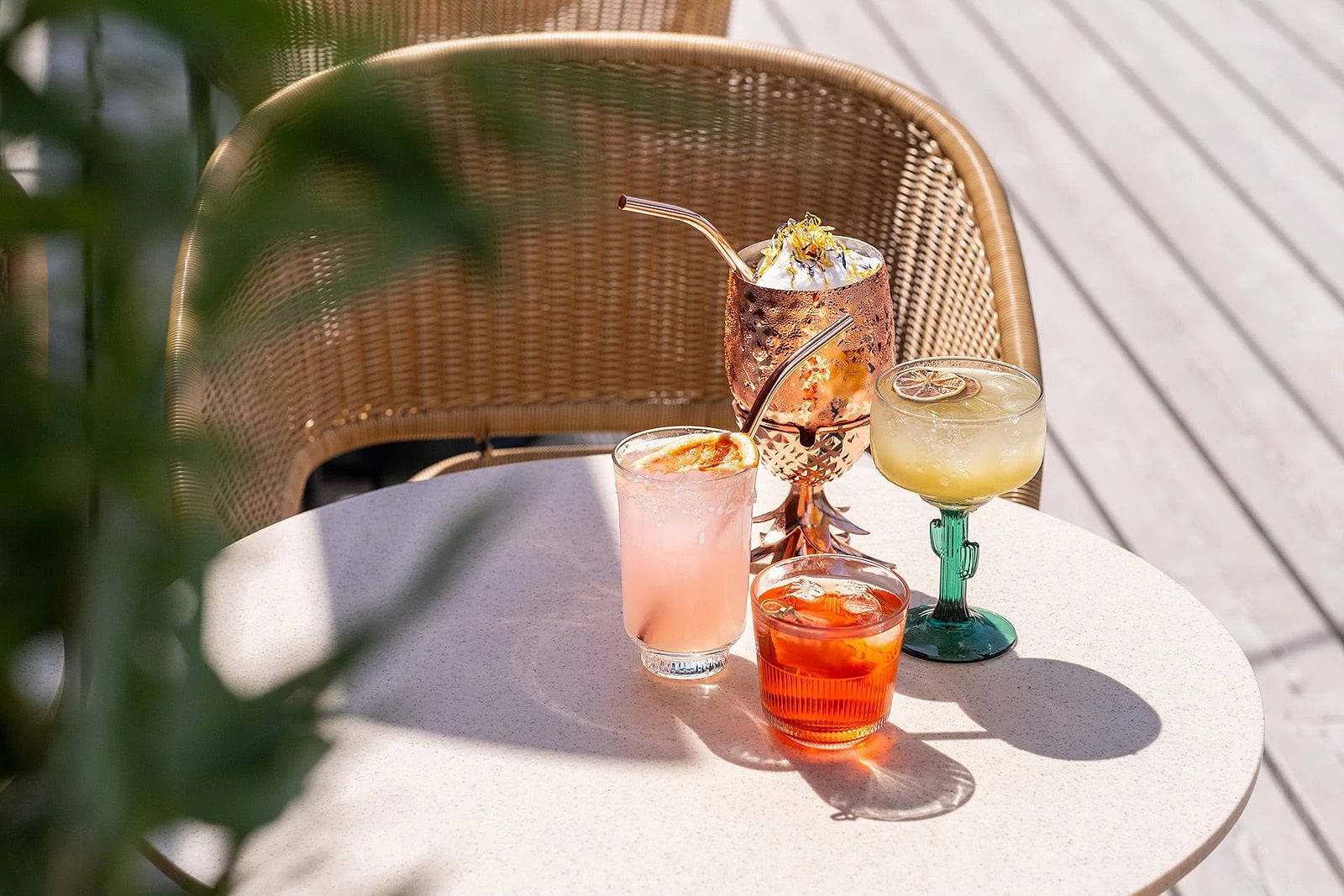 Four different cocktails on a rooftop bar table in the sun